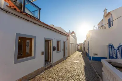 an alley with white buildings and the sun in the distance at tiny BEACH HOUSES - 2 min to Beach in Salema