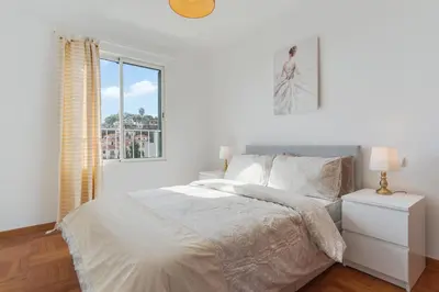 a white bedroom with a bed and a window at Camara de Lobos Apt by Holiday Rental Madeira in Câmara de Lobos