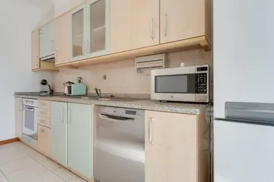 a kitchen with white cabinets and a microwave at Camara de Lobos Apt by Holiday Rental Madeira in Câmara de Lobos