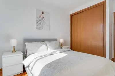a bedroom with a white bed and a wooden door at Camara de Lobos Apt by Holiday Rental Madeira in Câmara de Lobos