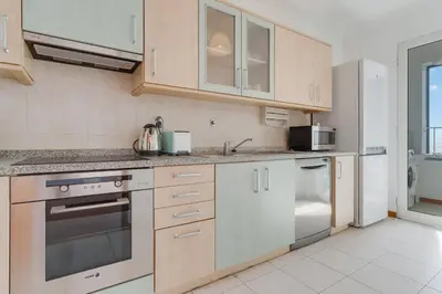 a kitchen with stainless steel appliances and white cabinets at Camara de Lobos Apt by Holiday Rental Madeira in Câmara de Lobos
