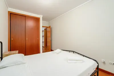 a bedroom with a white bed with a wooden cabinet at New Santa Cruz Airport & Downtown Apartment in Santa Cruz