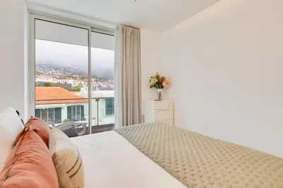 a bedroom with a bed and a large window at Plaza city center- Balcony amazing views in Funchal
