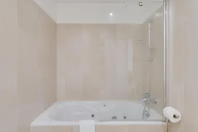 a white bathroom with a tub and a shower at Plaza city center- Balcony amazing views in Funchal