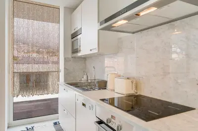 a kitchen with white cabinets and a large window at Plaza city center- Balcony amazing views in Funchal