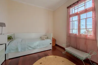 a bedroom with a bed and a window and a chair at Villa Flora by Holiday Rental Madeira in Estreito da Calheta