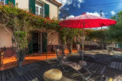 a patio with a red umbrella and chairs at Villa Flora by Holiday Rental Madeira in Estreito da Calheta