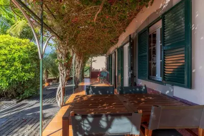 a deck with a table and chairs on a house at Villa Flora by Holiday Rental Madeira in Estreito da Calheta