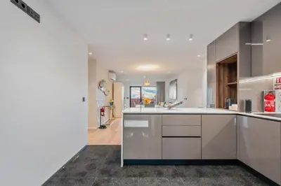 a large kitchen with white cabinets and a hallway at Apartamento Moderno T2 com Pátios e Acesso a Piscina in Funchal
