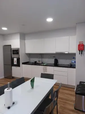 a kitchen with white cabinets and a white table and chairs at Visconde II F in Ribeira Brava
