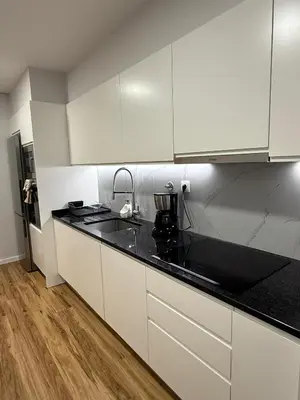 a kitchen with white cabinets and black counter tops at Visconde II F in Ribeira Brava