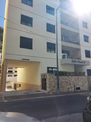 a white building with a stone wall in front of it at Visconde II F in Ribeira Brava