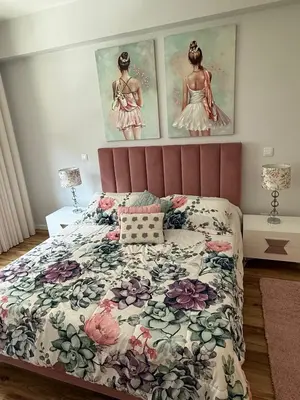 a bedroom with a bed with a floral bedspread and two pictures of girls at Visconde II F in Ribeira Brava