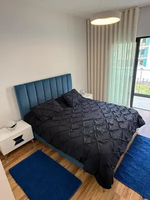 a bedroom with a bed with a black comforter and blue rugs at Visconde II F in Ribeira Brava