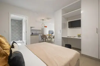 a white bedroom with a bed and a kitchen at Sunflower Gem by Homie in Caniço