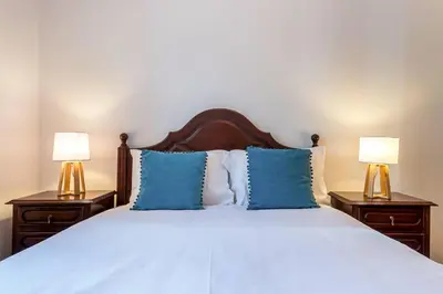 a bedroom with a bed with blue pillows and two lamps at Casa da Georgina by GALMI in Arco da Calheta