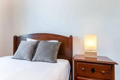 a bed with a wooden headboard and a lamp on a night stand at Casa da Georgina by GALMI in Arco da Calheta