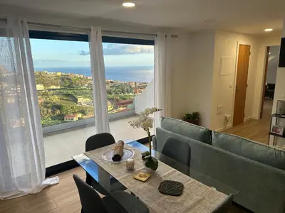 a living room with a couch and a table and a large window at Refugio da Ponta do Sol 2 - Madeira Inn Group in Ponta do Sol