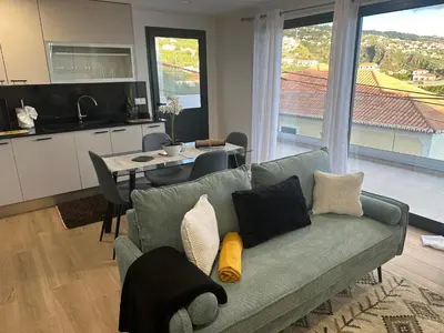 a living room with a green couch and a kitchen at Refugio da Ponta do Sol 2 - Madeira Inn Group in Ponta do Sol