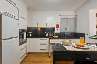 a kitchen with white cabinets and a table with a plate of food at Quinta do Checa by Homie in Quinta Grande