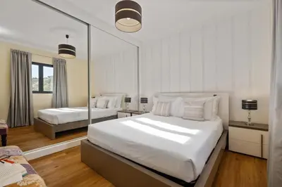 a white bedroom with two beds and a mirror at Quinta do Checa by Homie in Quinta Grande