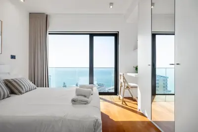 a bedroom with a large white bed and large windows at Ocean Vista- T2 Funchal in Bicas
