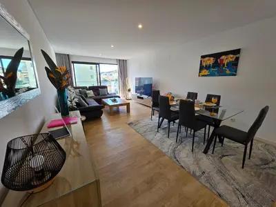 a living room with a table and chairs and a couch at Glendeira Lux Apartment in Caniço