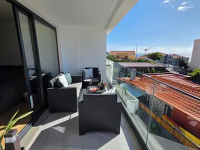 a balcony with a couch and chairs on a building at Glendeira Lux Apartment in Caniço