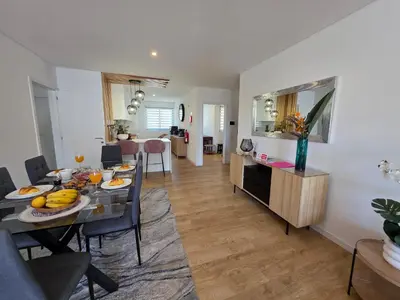 a dining room and living room with a dining table at Glendeira Lux Apartment in Caniço