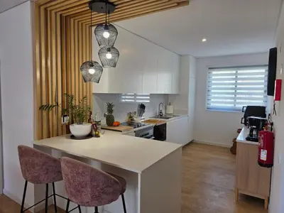 a kitchen with a counter and two bar chairs at Glendeira Lux Apartment in Caniço