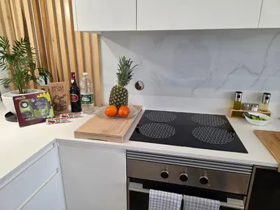 a kitchen with a stove and a pineapple on a cutting board at Glendeira Lux Apartment in Caniço