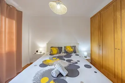 a bedroom with a large white bed with yellow and black pillows at Ocean Life by YOUR KEY MADEIRA in Caniço