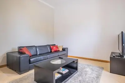 a living room with a black leather couch and a tv at Country Escape in Ribeira Brava