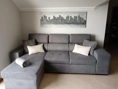 a living room with a gray couch and a painting at Vanda House com 2 Quartos Vista Mar e montanha no centro da Ilha in Tábua