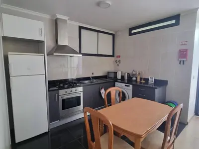 a kitchen with a table and a stove and a refrigerator at Apto Vista Baía Machico by Susys Holidays in Machico