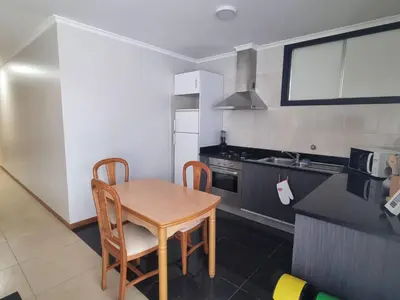 a small kitchen with a wooden table and chairs at Apto Vista Baía Machico by Susys Holidays in Machico