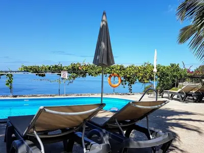 two chairs and an umbrella next to a swimming pool at Quinta Golfinho - Casa Frangipani in Arco da Calheta