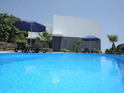 a large blue swimming pool with umbrellas and chairs at Quinta Golfinho - Casa Frangipani in Arco da Calheta