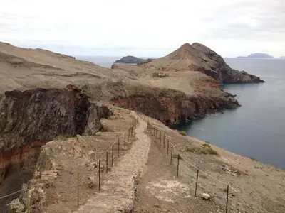 a path on the side of a cliff next to the water at Quinta Golfinho - Casa Frangipani in Arco da Calheta