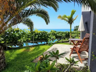 a patio with a bench and a view of the ocean at Quinta Golfinho - Casa Frangipani in Arco da Calheta