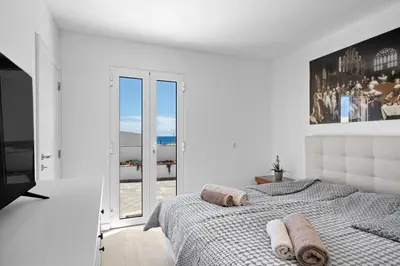 a white bedroom with a bed and a large window at Casa Do Cabeco in Lapeiras