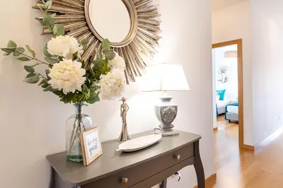 a table with a vase of flowers and a mirror at GuestReady - Perfect family home in Caniço in Santa Cruz