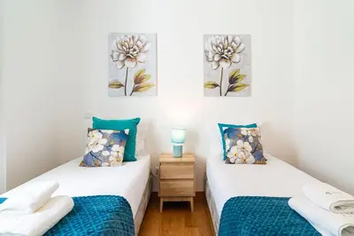 two twin beds in a room with two paintings on the wall at GuestReady - Perfect family home in Caniço in Santa Cruz