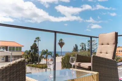 a patio with a glass table and chairs on a balcony at GuestReady - Perfect family home in Caniço in Santa Cruz
