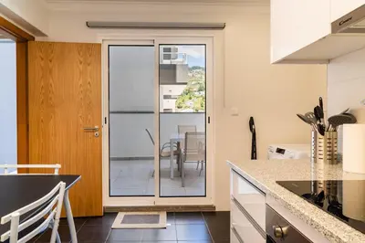 a kitchen with a sliding glass door leading to a balcony at GuestReady - The perfect hideout in Caniço in Caniço