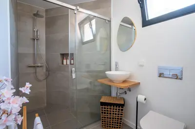 a bathroom with a shower with a sink and a mirror at Golden Tide in Machico