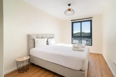 a white bedroom with a large bed and a window at GuestReady - Seaview Escape in Câmara de Lobos