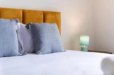 a bed with blue and white pillows and a green lamp at GuestReady - Lovely experience in Funchal in Funchal