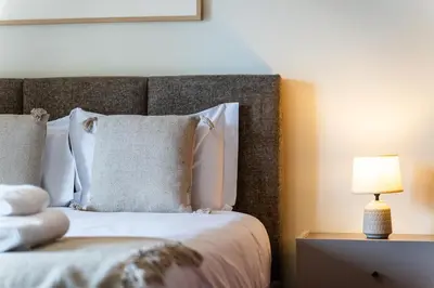 a bed with white pillows and a table with a lamp at GuestReady - Lovely experience in Funchal in Funchal