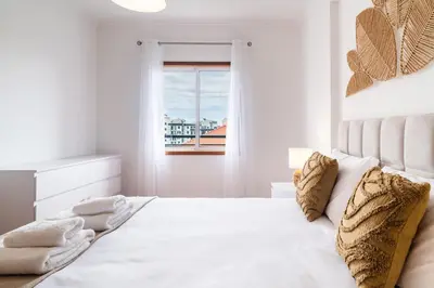 a white bedroom with a large bed with a window at GuestReady - Peaceful haven in Funchal in Funchal